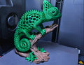 3D printed green voronoi chameleon sculpture on a branch