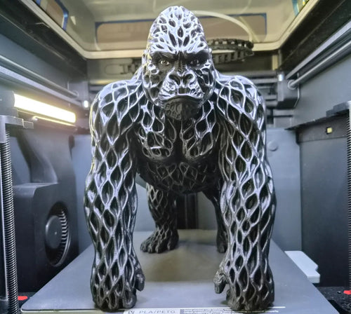 3D printed Voronoi gorilla sculpture in glossy black with geometric lattice body, fresh off the print bed